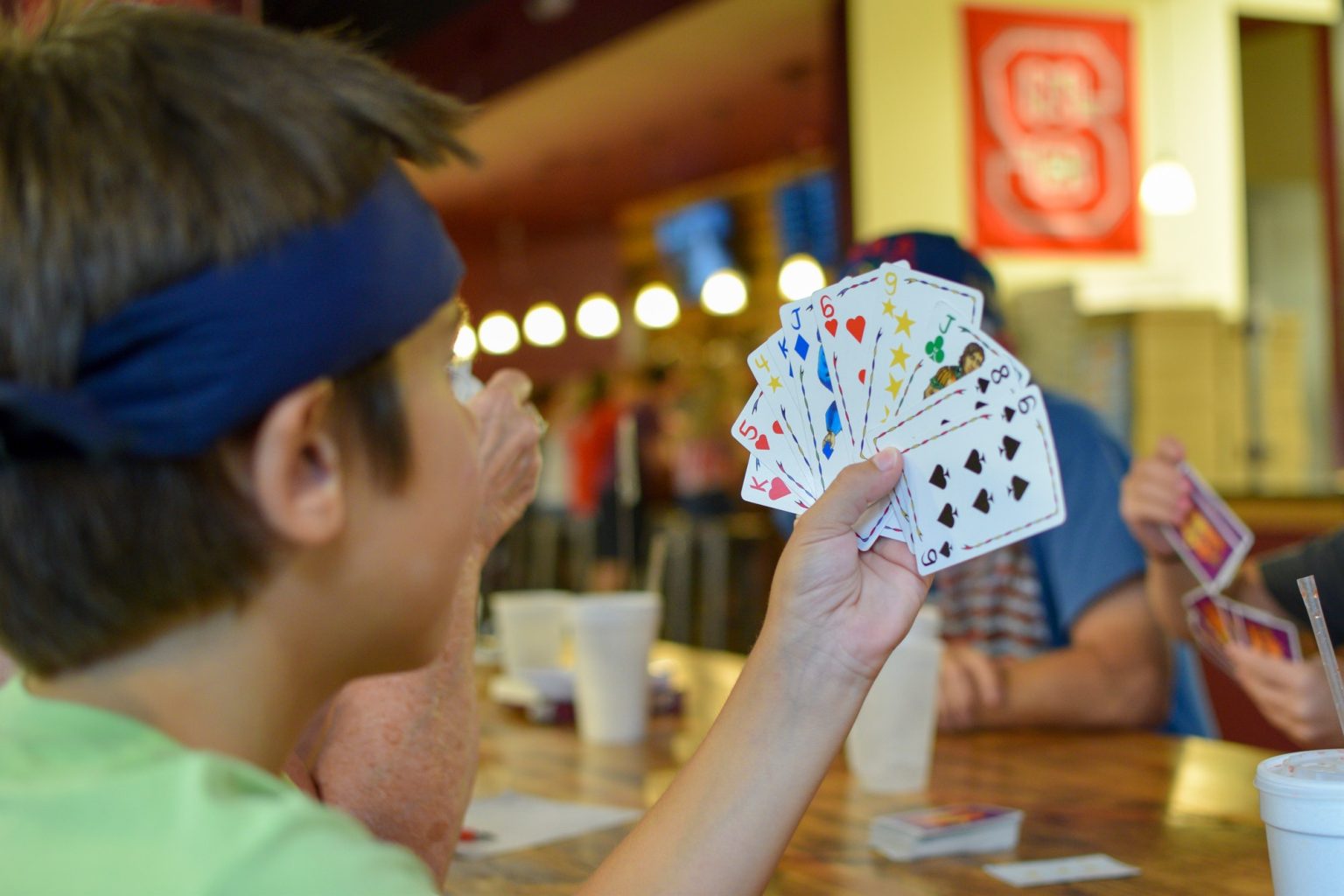 Child playing cards with his family at a restaurant table